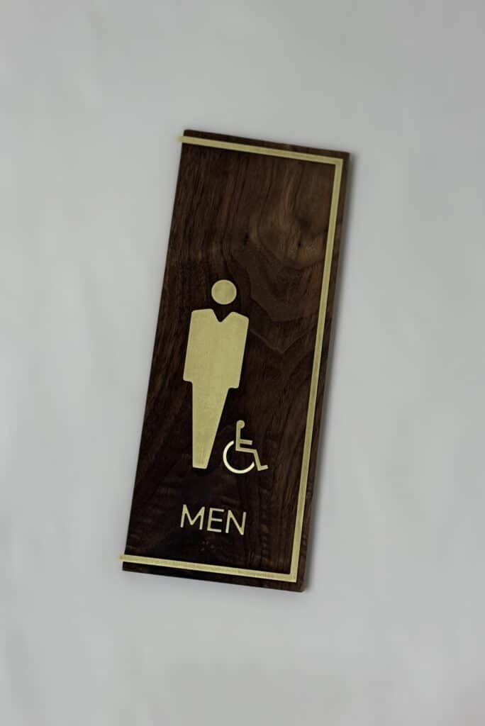 brass border, and pictograms and letters on walnut mens restroom sign