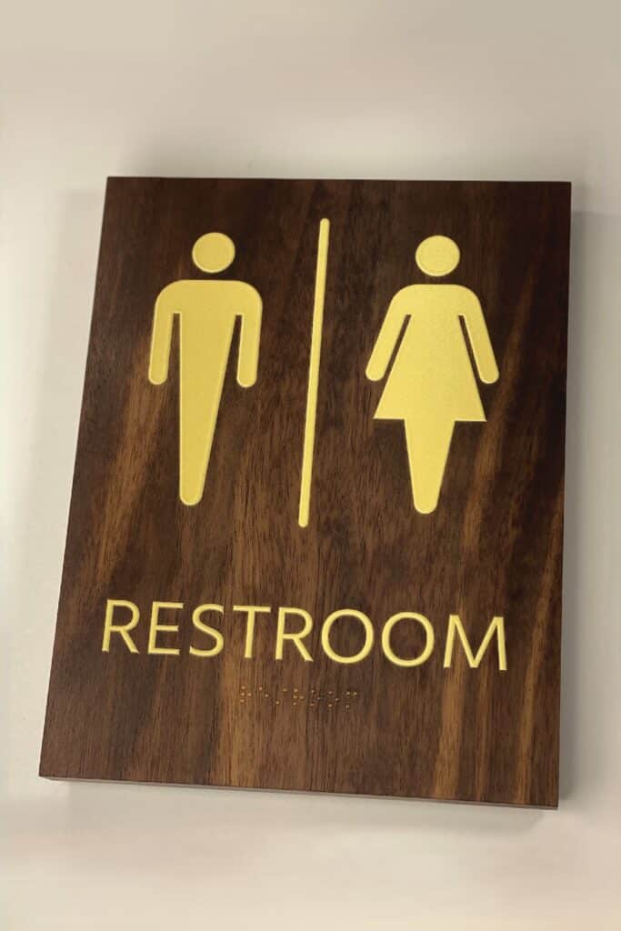 walnut wood restroom sign with yellow ADA letters saying "restroom"